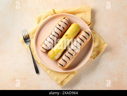 Different tasty glazed eclairs served on color textured table, top view Stock Photo