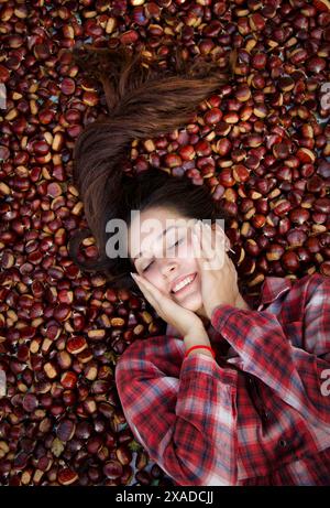 portrait of beautiful woman smiling with closed eyes lying down on chestnut carpet Stock Photo