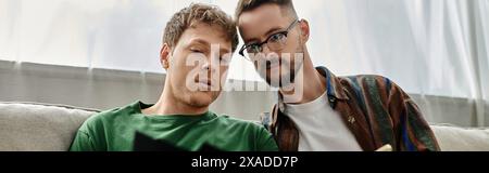 Two men, part of a creative team, casually sit atop a modern couch in a designer workshop. Stock Photo