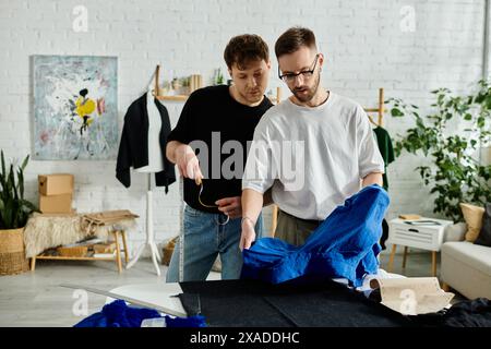 Two men in designer workshop, collaborating on trendy attire. Stock Photo