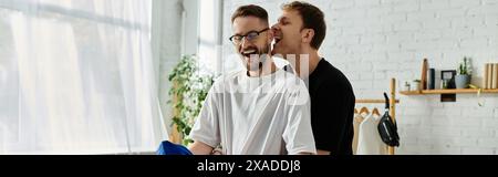 Two fashion designers embrace in their atelier, having fun, sharing ideas and passion for trendy attire. Stock Photo