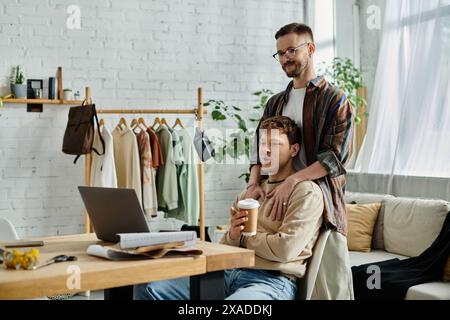 A man sips coffee at a table with his partner, discussing their latest designs. Stock Photo