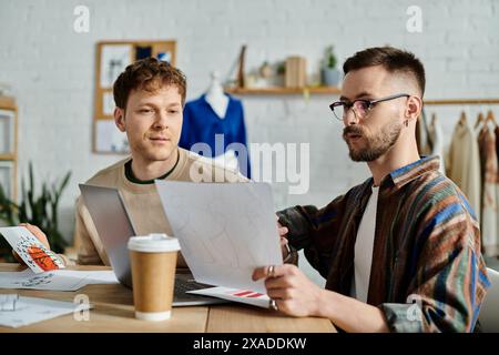 Two men in a designer workshop focus intently on creating trendy attire together. Stock Photo