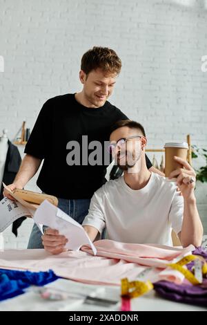 Two men in love, creatively collaborating over a piece of paper at a stylish table. Stock Photo