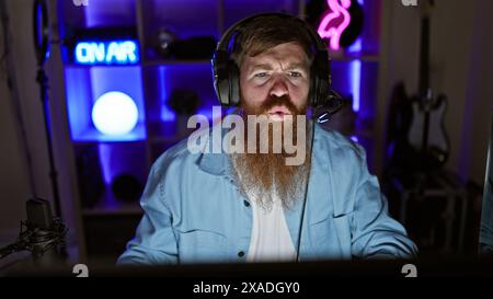 Handsome irish redhead streamer locked in serious game on his decked-out gaming rig, night streaming session from his decked-out gaming room Stock Photo