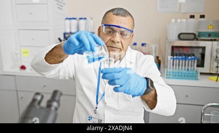 Mature hispanic man scientist analyzing liquids in lab Stock Photo