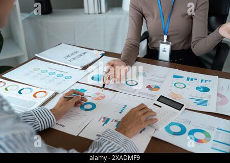 Businesswoman using a calculator to calculate numbers on a company's financial documents, she is analyzing historical financial data to plan how to Stock Photo