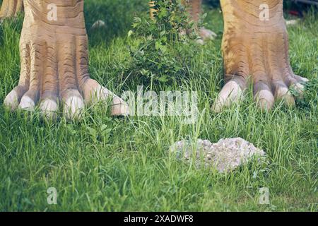 Two dinosaur paws in the Jurassic amusement park, where there is a place to copy. Paws with claws on a background of green grass. High quality photo Stock Photo