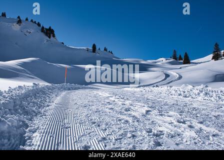 A snow covered mountain with a ski run down the side. The sky is clear and blue. The snow is fresh and untouched Stock Photo
