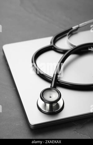 Modern laptop and stethoscope on black table, closeup Stock Photo