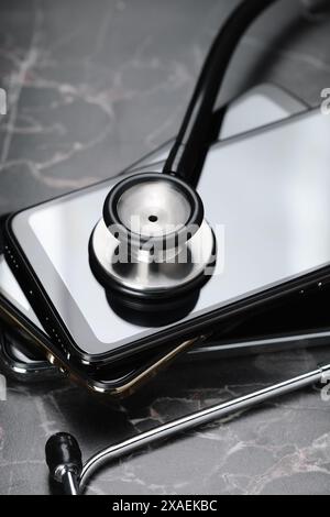 Stack of modern smartphones and stethoscope on black table, closeup Stock Photo