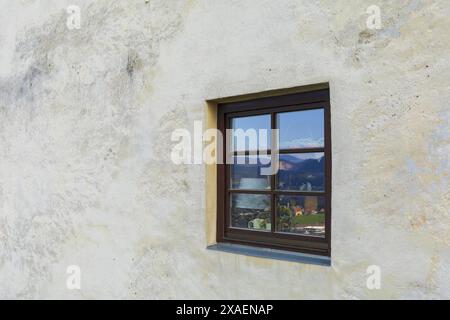 photography of a white stone wall with an old window with blue sky and mountains reflection Stock Photo