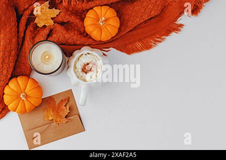 Cozy fall composition with spiced latte in a pumpkin shaped mug, decorative small pumpkins and plaid, overhead view Stock Photo