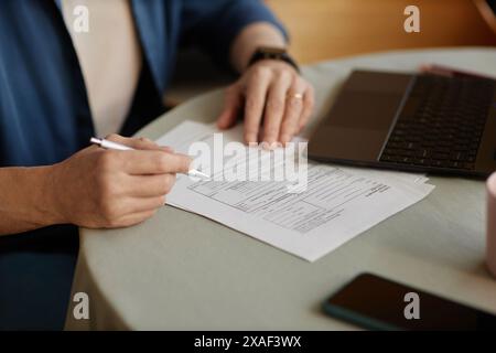 Close up of unrecognizable senior woman signing financial papers and doing taxes at home copy space Stock Photo