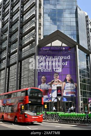 City Of London, Gbr. 06th June, 2024. City of London. GBR. 06 June 2024. TeamGB weightlifting team announcement. 250 bishopsgate. City of London. A slow shutter spped photo of a redLondon bus [assing the bill board in front of the Nat West offices during the Team GB Weightlifting Team Announcement for the Paris24 Olympics at Nat West, 250 Bishopsgate, London, UK. Credit: Sport In Pictures/Alamy Live News Stock Photo