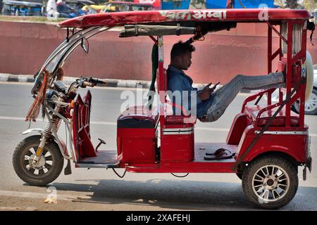 Delhi, India: Street scene in the old city centre of Delhi. Rickshaw driver on the phone waiting for customers Stock Photo