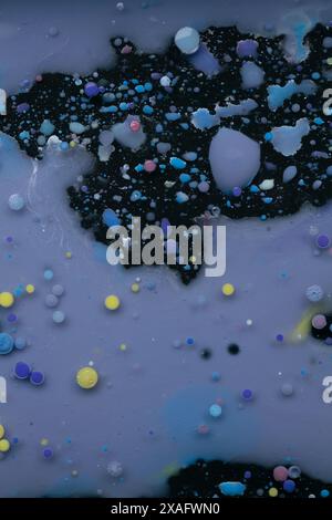 A myriad of oil droplets intermingling with water, creating a mesmerizing effect reminiscent of a galaxy. Stock Photo