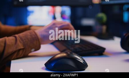 Focus on computer peripherals used by programmer to write lines of code on PC screen. Close up shot of keyboard and mouse used by developer working on fixing database errors, camera B Stock Photo