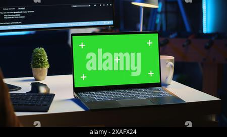 Green screen laptop in home office used for developing software applications. Mockup notebook used by teleworking IT specialist for programming, camera A close up panning shot Stock Photo