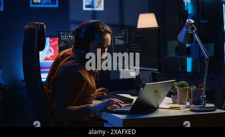 Fatigued developer working overnight at home, rubbing eyes while taking break from coding, feeling sleepy. Tired IT admin exhausted from too much screen time, pausing tasks to rest, camera A Stock Photo