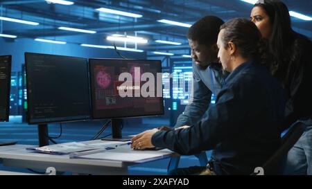 System administrator in server room workplace requesting assistance from colleagues during malware attack. IT support worker asking for help from colleagues to protect data center from hackers Stock Photo