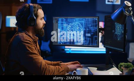 Developer updating artificial intelligence neural networks, drinking coffee and listening music in personal office. IT expert enjoying hot beverage and audio podcasts while writing AI code, camera A Stock Photo