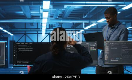 Manager overseeing IT technicians in server hub repairing equipment storing datasets. Team leader at work in data center supervising workers mending rigs doing computational operations Stock Photo