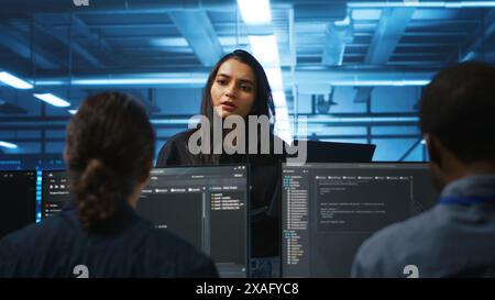 Supervisor in server hub managing multiracial team of programmers looking for equipment misconfigurations. Manager coordinating tech specialists fixing data center damages Stock Photo