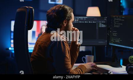 Stressed engineer feeling pressed by deadline, thinking how to finish developing code on PC. IT specialist brainstorming ways of solving database errors, working hard, drinking coffee, camera A Stock Photo