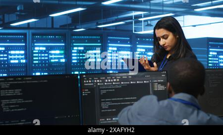 Manager overseeing server room, walking around with checklist on notepad, troubleshooting hardware. Supervisor doing inspection in server hub, monitoring energy consumption across rigs Stock Photo