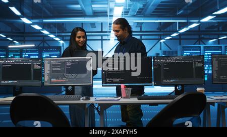 Multiracial colleagues in server hub workspace collaborating to fix servers providing computing resources for workloads. Engineers doing brainstorming while supervising data center supercomputers Stock Photo