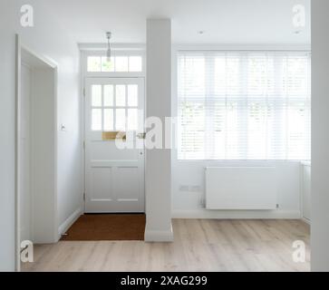 Minimalist, white painted front door and entrance hallway of an Edwardian house converted into flats in north London. Stock Photo