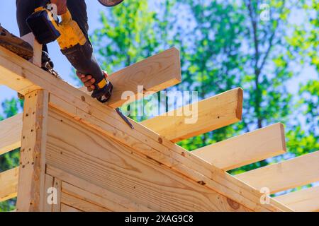 During construction, contractor uses cordless reciprocating saw to cut beams Stock Photo
