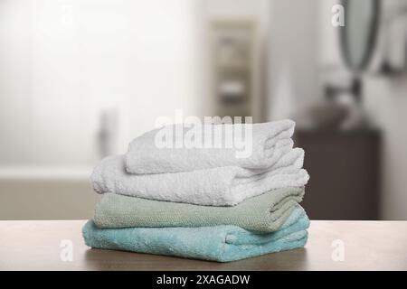 Folded fresh towels on wooden against blurred bathroom interior Stock Photo