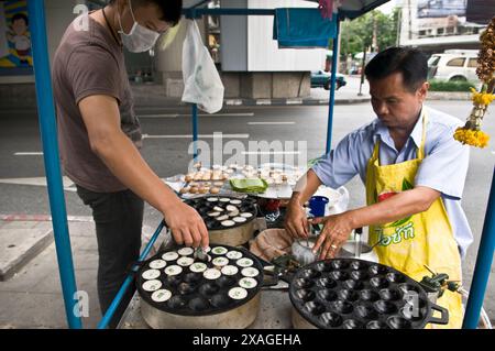 Khanom krok being cooked in a large indented pan. Bangok, Thailand. Stock Photo