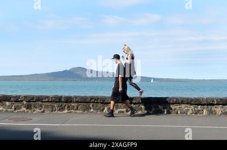 A couple walking on the waterfront promenade by the St Heliers beach in Auckland, New Zealand. Stock Photo