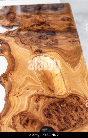 Live edge elm burl slab table top with central epoxy resin river on sawhorses in professional workshop close view Stock Photo
