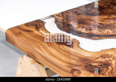Live edge elm burl slab table top with central epoxy resin river on sawhorses in professional workshop close view Stock Photo