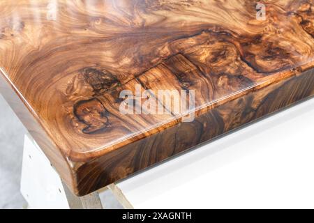 Live edge elm burl slab table top with central epoxy resin river on sawhorses in professional workshop close view Stock Photo