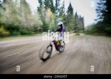 Motion blur. Cyclist man riding electric mountain bike outdoors. Male tourist biking along trail in the forest. Concept of sport, active leisure and nature. Stock Photo