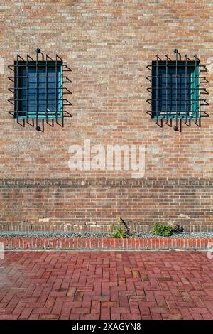 The barred windows on the exterior wall of an old brick building Stock Photo