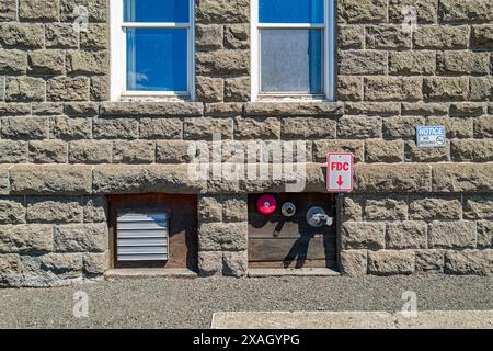 FDC sign pointing to the fire department connections for a sprinkler system on the outer wall of an old stone building Stock Photo