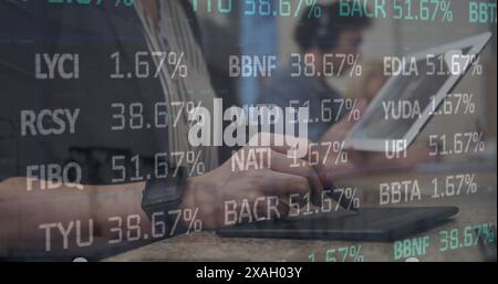 Image of stock market data processing against mid section of a woman using graphic tablet Stock Photo