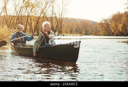 Lake, senior couple and rowing in nature with canoe for explore, adventure or retirement activity. Outdoor, river and elderly woman with man on boat Stock Photo