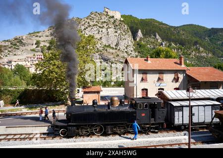 AERIAL VIEW from a 6-meter mast. The steam train before departure from the Entrevaux train station.  Entrevaux Castle at the clifftop. France. Stock Photo