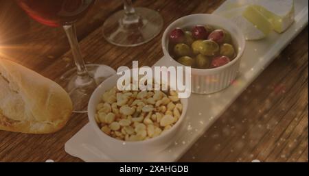 Image of lights over wine and snacks arrangement on wooden table Stock Photo