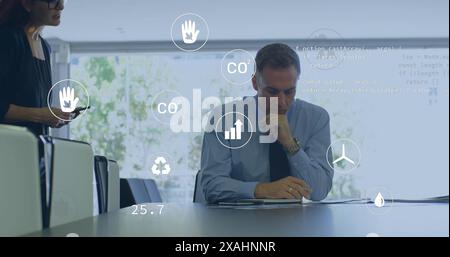 Image of eco icons and data processing over diverse business people in office Stock Photo