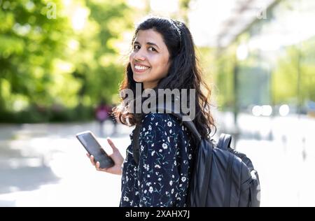 Smiling young woman using her smartphone in the city Stock Photo