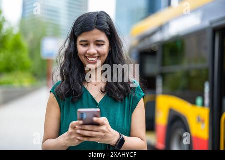 Young woman using smart phone at the bus stop in the city Stock Photo