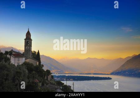 Beautiful Church Tower with Panoramic View on the Mountain Peak over Lake Maggiore with Mountain in Sunrise in Ronco sopra Ascona, Ticino, Switzerland Stock Photo